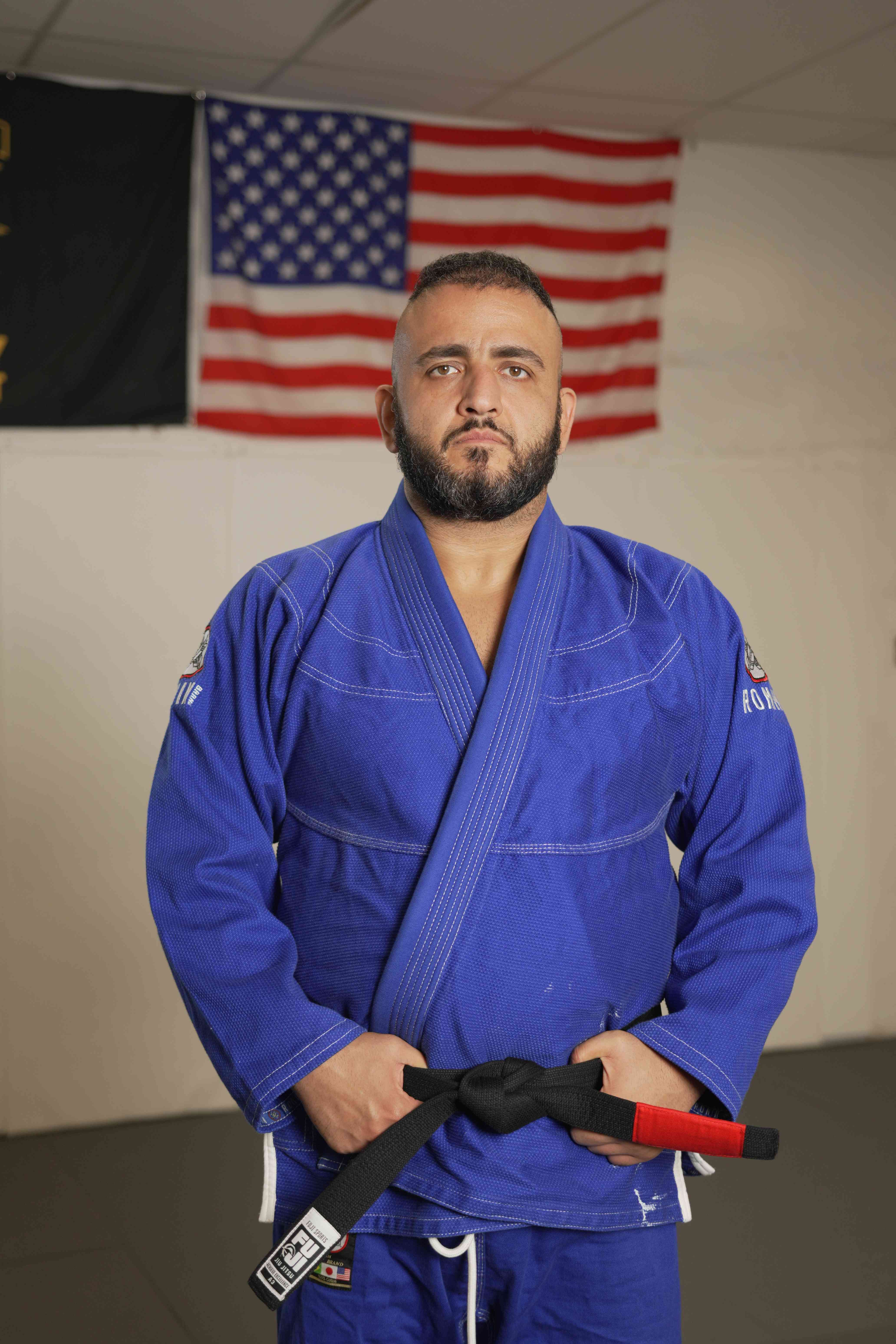 Mike Rakshan, founder and head coach of Immortals Jiu Jitsu, standing in a blue gi.