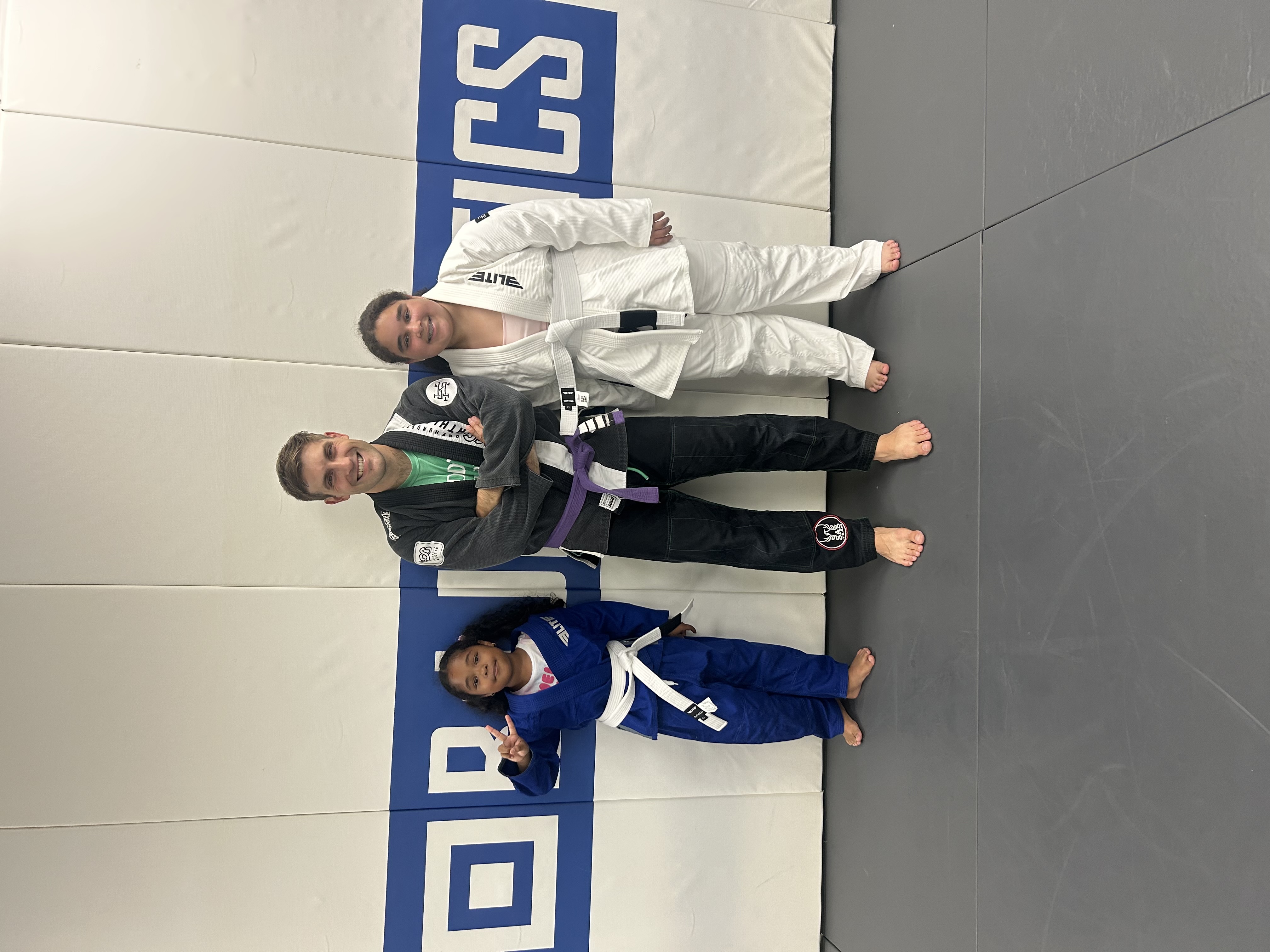 Patrick Campomizzi, coach at Immortals Jiu Jitsu, on the mats with two young students.