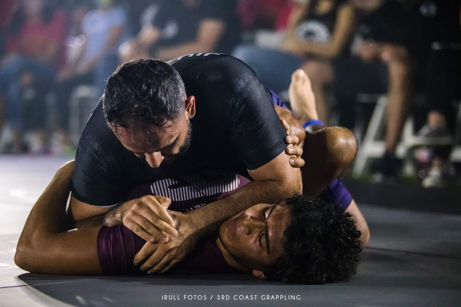 An Immortals athlete controlling an opponent on the ground during a live grappling competition match.
